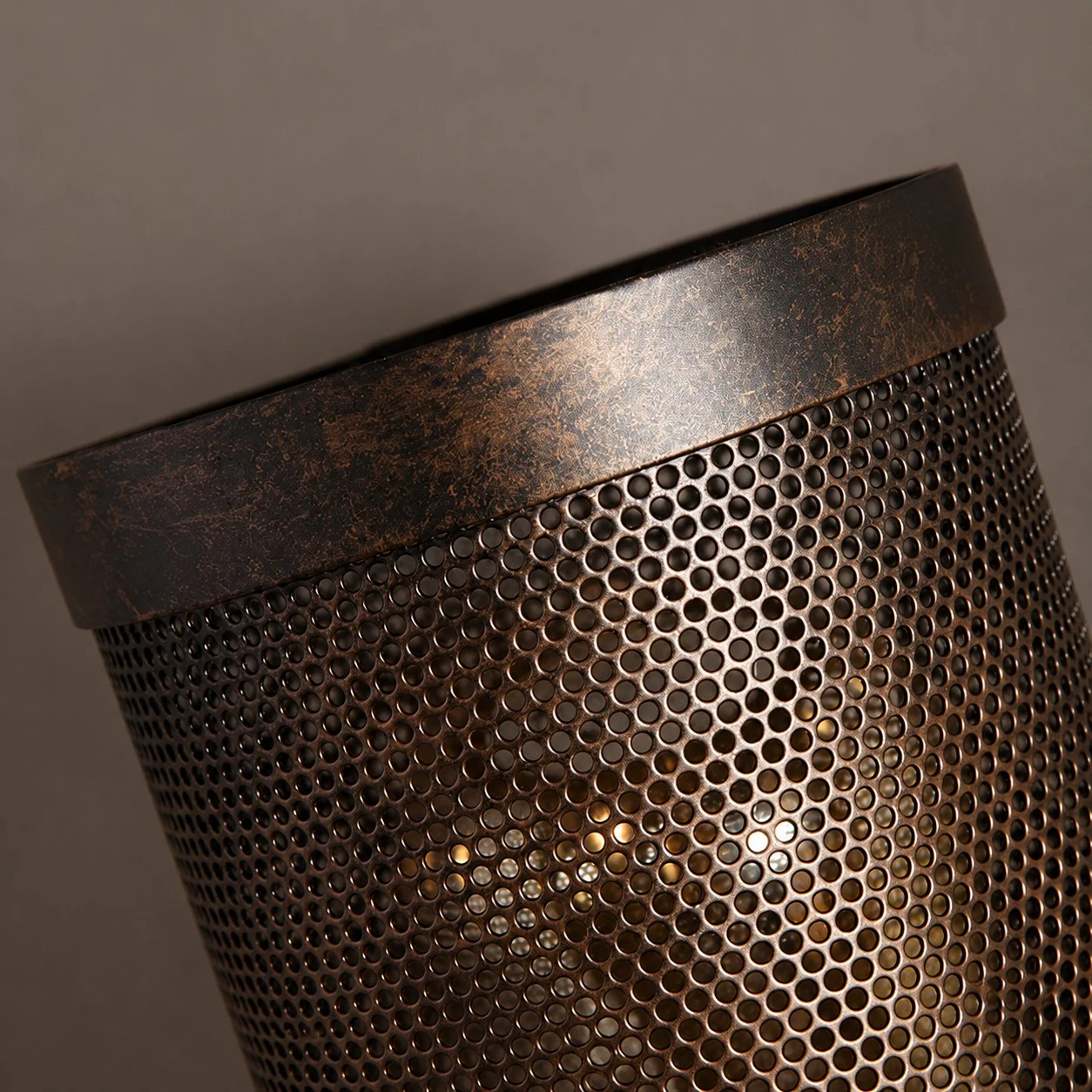 Bagliore caldo della lampadina visibile attraverso il paralume metallico perforato